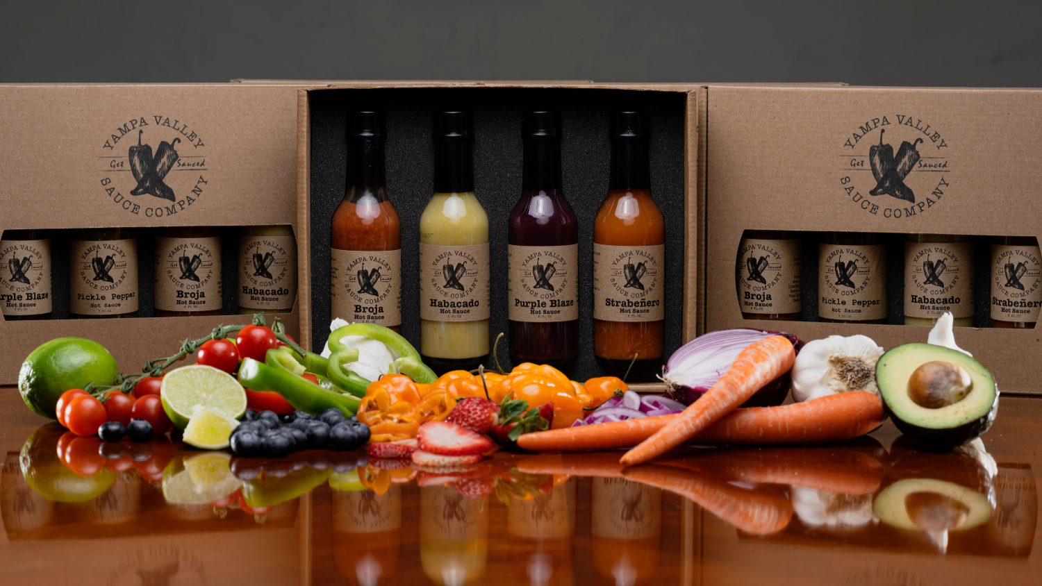 Assorted bottles and fresh produce on a reflective surface with 'Yampa Valley' branding