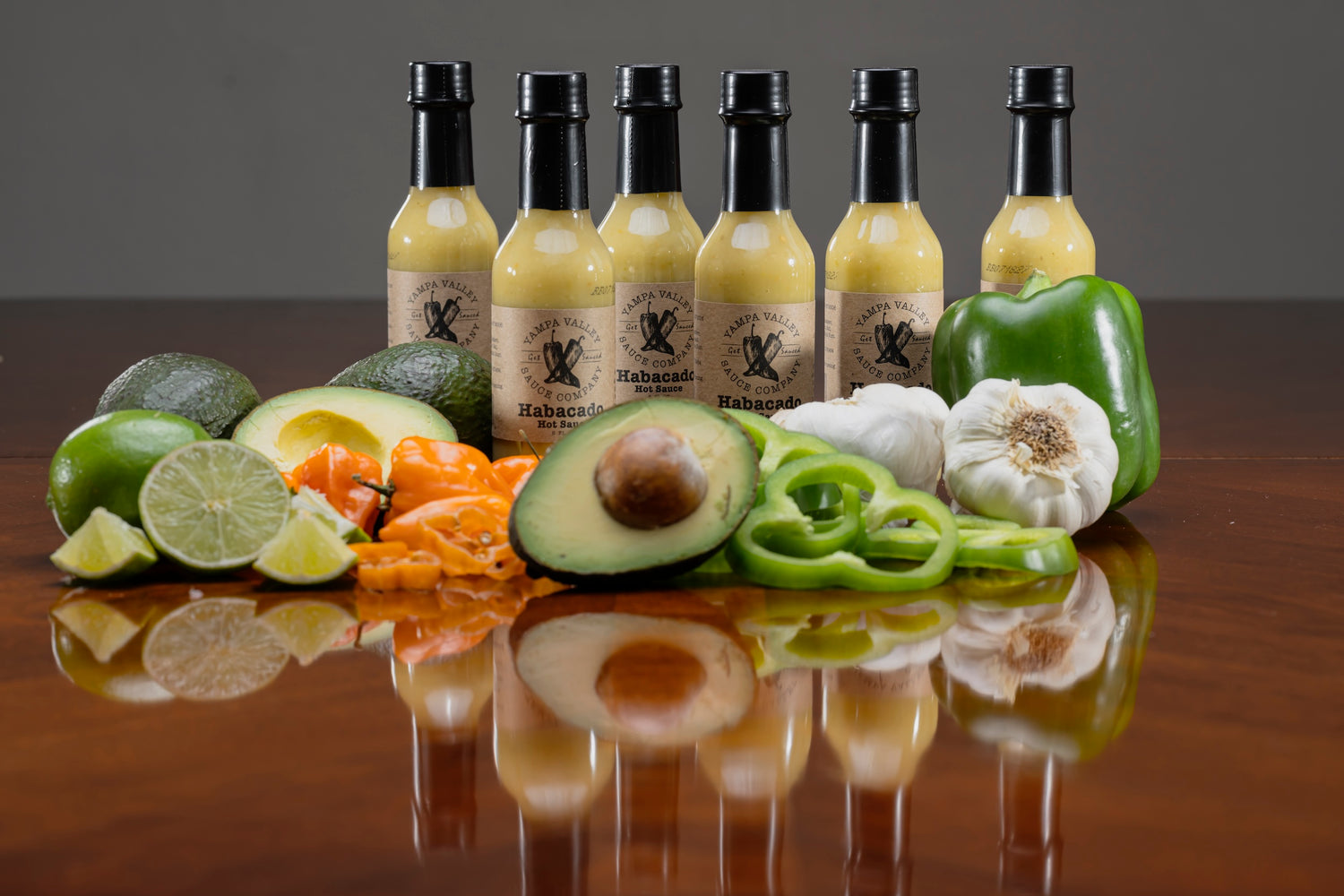 lime, habanero, avocado, green bell pepper in front of habacado avacado hot sauce bottles