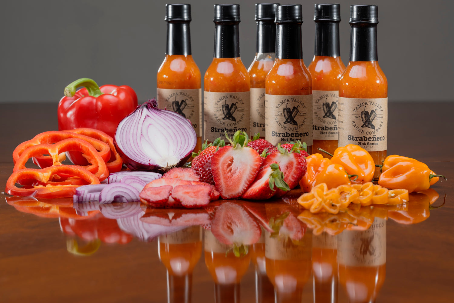 Hot sauce bottles with ingredients on a reflective surface